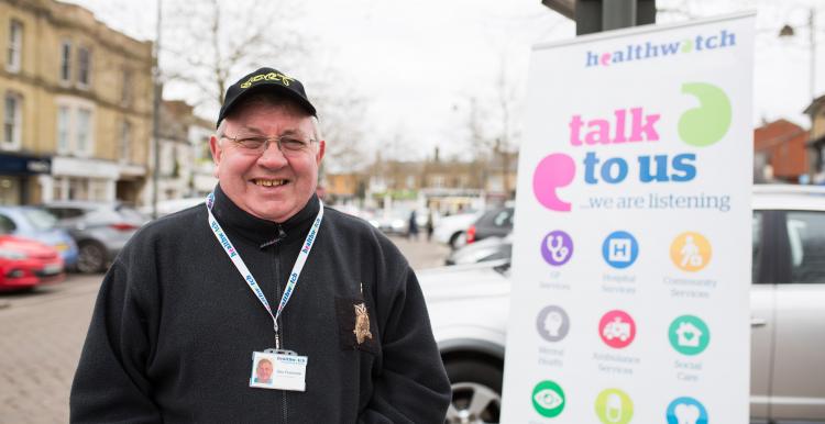 male volunteer standing with Healthwatch banner