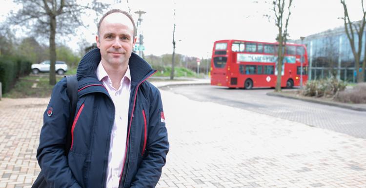 man stood outside with a bus in the background