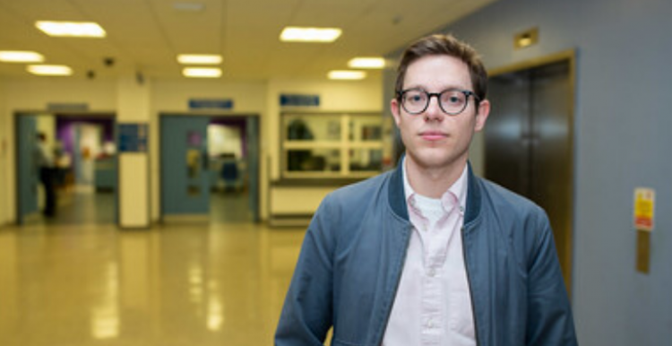 Young man standing in hospital corridor