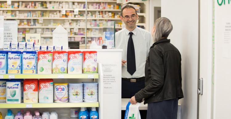 Lady holding collected prescription talking to a pharmacist in the pharmacy
