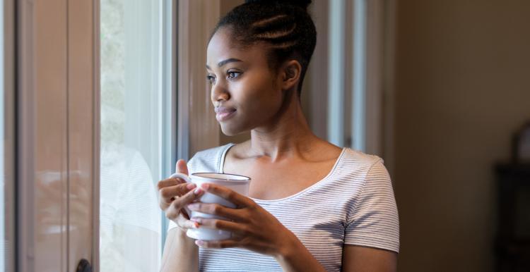 Lady holding cup staring out the window