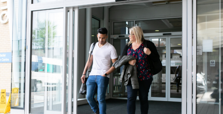 man and woman exiting a building talking