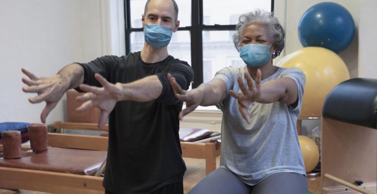 a man and woman sitting on exercise balls. Their arms are stretched out in front of them.