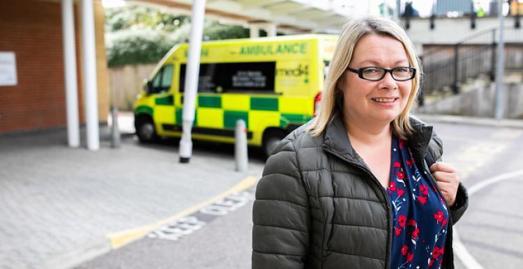 woman posing for camera with ambulance in the background