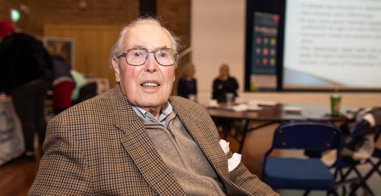 Older man sitting down facing the camera