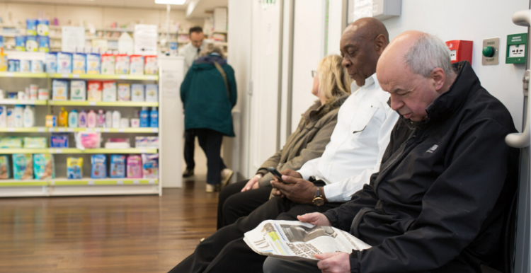 Three people sitting waiting at a pharmacy
