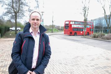 man stood outside with a bus in the background