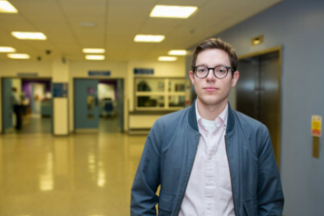 Young man standing in hospital corridor