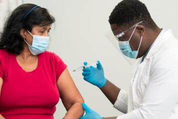 man in white lab coat vaccinating a woman