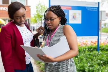 Two people look at a folder outside a hospital