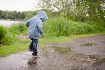 child splashing in puddles