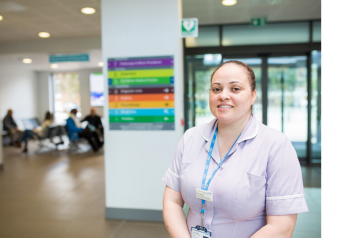 Nurse standing in a hospital with signage behind her