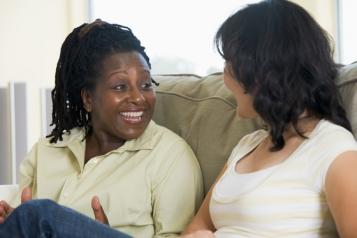 Two ladies sitting on a sofa talking