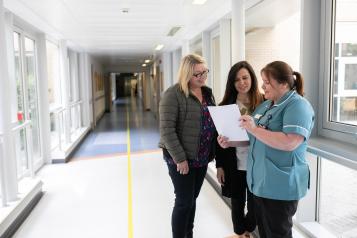 Three women talking in hospital corridor