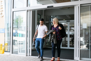 man and woman exiting a building talking
