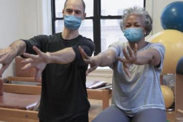 a man and woman sitting on exercise balls.  Their arms are stretched out in front of them.