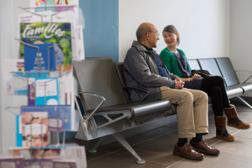 Young woman and older man sitting in hospital waiting seats