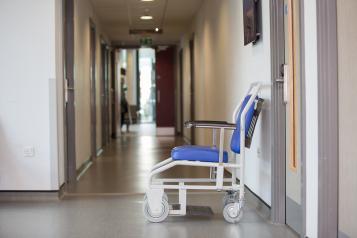 Empty wheel chair against a wall in hospital corridor