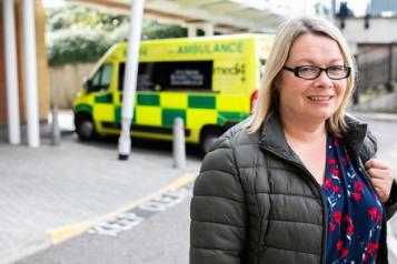 woman posing for camera with ambulance in the background