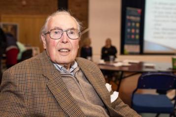 Older man sitting down facing the camera