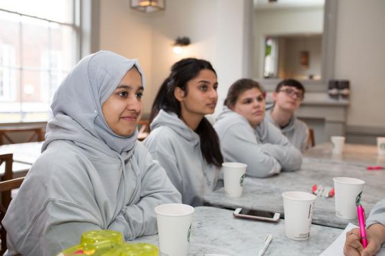 Three females sitting at a desk listening