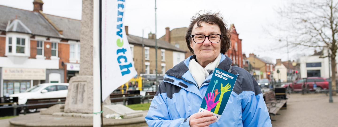 Healthwatch volunteer holding a Healthwatch volunteering leaflet