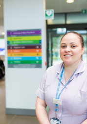 Nurse standing in a hospital with signage behind her