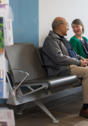Young woman and older man sitting in hospital waiting seats